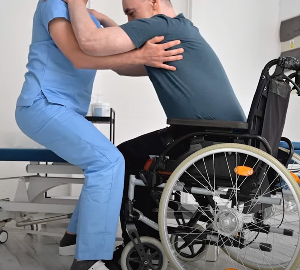 Physical therapist lifting patient out of wheelchair